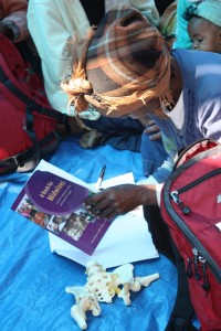 Woman looking at Hesperian book and model of pelvis