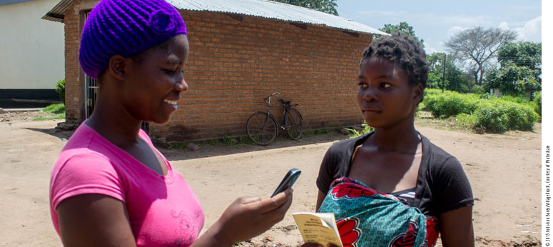 two women talking about family planning one is holding a phone in a rural area 