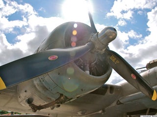 An aircraft engine with blue sky and white clouds in the background