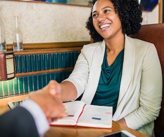 Smiling business woman shaking hands with another person. 