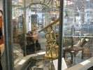 Photo of a student looking through a historical telescope on display in a glass case.