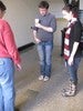 Photo of three students in a hallway looking at a mirror on the floor between them.