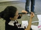 Photo of a student on the floor sighting along a tube against which she's holding two straws.