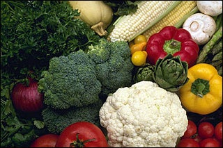 A photograph containing a lot of vegetables, including broccoli, cauliflower, red and yellow peppers, tomatoes, corn, and mushrooms. 