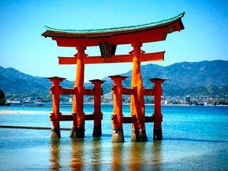 An oriental red wooden structure standing in a lake surrounding with mountains