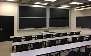 A view of a classroom, looking toward the chalkboards in the front of the room.