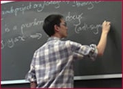 A men standing in front of a blackboard and writing on the blackboard.