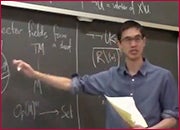 A men standing in front of a blackboard and pointing the blackboard with right hand.