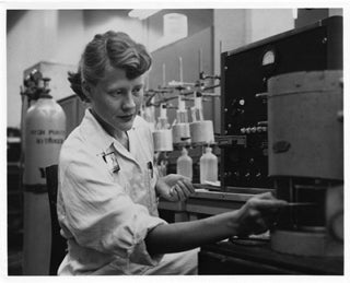 Black and white photo of a young woman working in a chemistry lab.