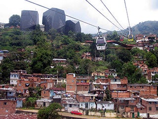 Photo of an informal settlement in Medellin, Colombia with a public library in the background and aerial cable cars above.