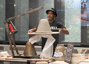 Man holding a bell shaped ceramic item on a slab.