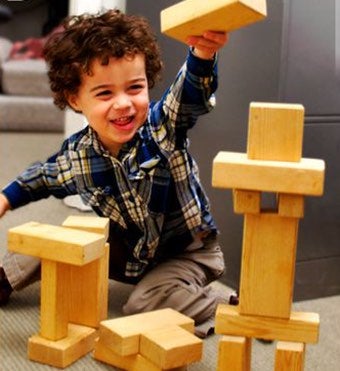 Photo of a young boy building a tower out of wooden blocks.